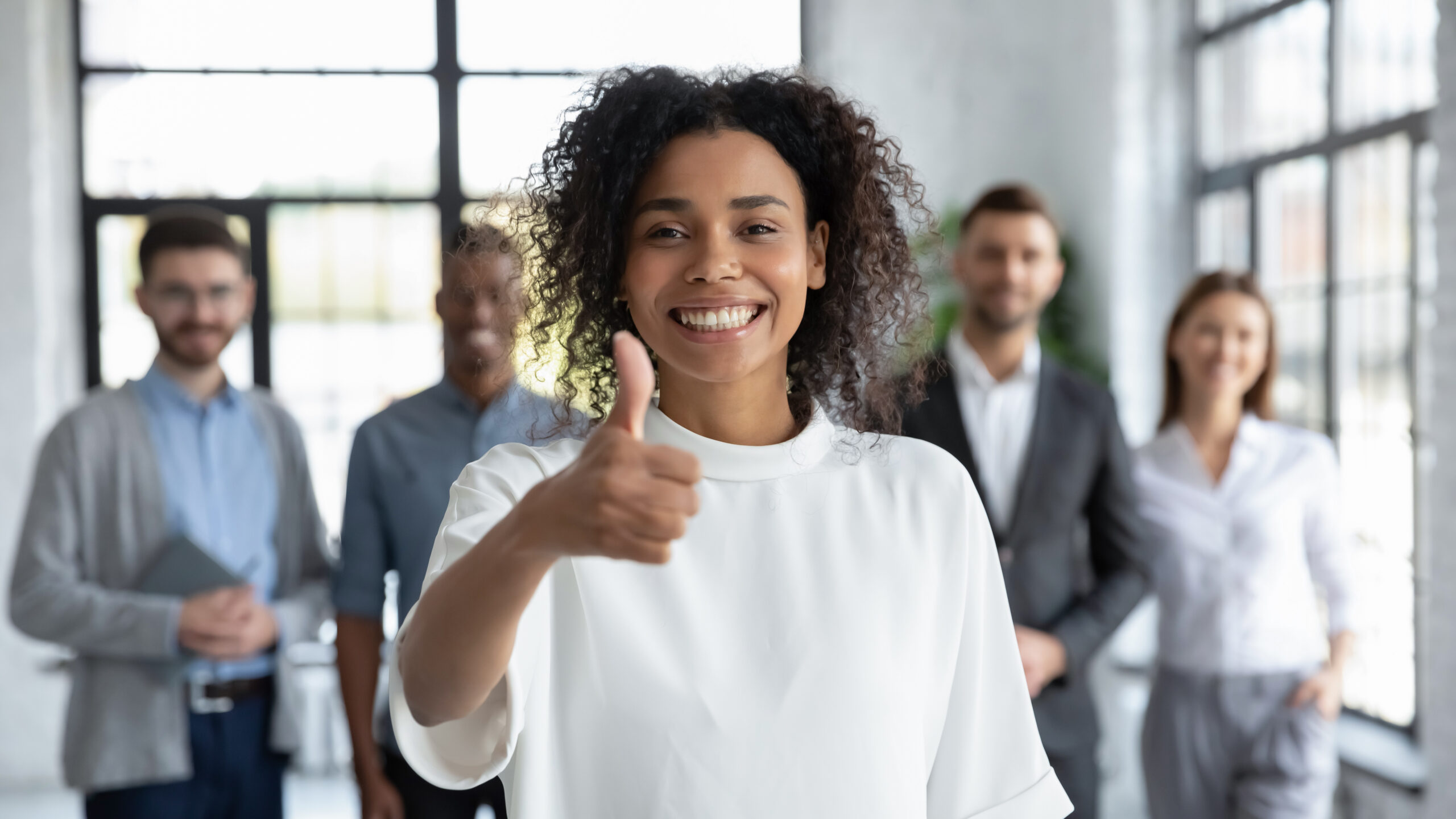 cheerful young female office worker giving a thumbs up
